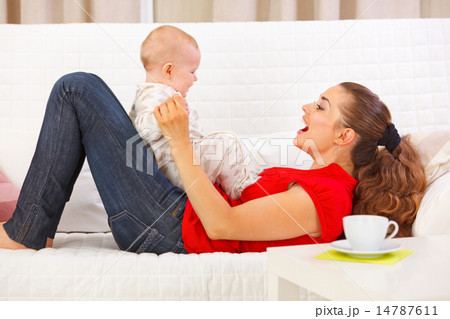 Smiling mother and cute baby playing on divan 14787611