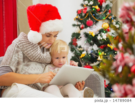Mother and baby girl using tablet PC near Christmas tree Mother and baby girl using tablet PC near Christmas tree 14789084