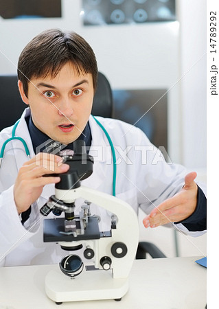 Confused male researcher pointing on microscope Confused male researcher pointing on microscope 14789292