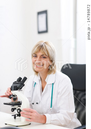 Smiling senior doctor woman working with microscope at laborator Smiling senior doctor woman working with microscope at laborator 14789872