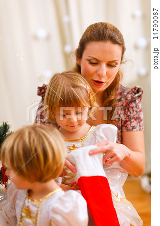 Mother looking with twins daughters inside of Christmas socks 14790087