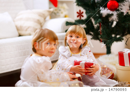 Two girls sitting with presents near Christmas tree 14790093