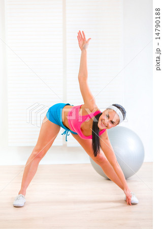 Smiling healthy young girl doing fitness exercises at home. 14790188
