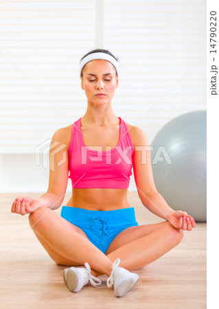 Concentrated beautiful girl doing yoga exercises on floor Concentrated beautiful girl doing yoga exercises on floor 14790220