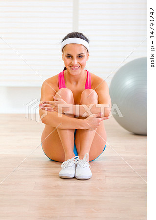 Smiling fit girl in sportswear sitting on floor at home Smiling fit girl in sportswear sitting on floor at home 14790242