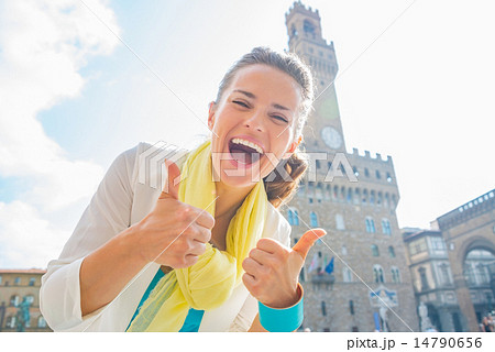 Happy young woman showing thumbs up in front of palazzo vecchio Happy young woman showing thumbs up in front of palazzo vecchio 14790656
