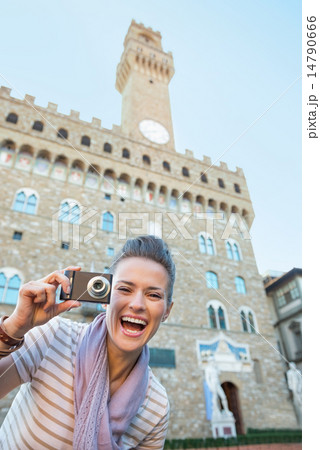 Portrait of smiling young woman with photo camera in front of pa Portrait of smiling young woman with photo camera in front of pa 14790666
