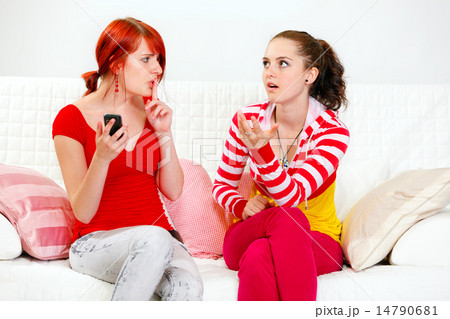 Girl with mobile showing silence gesture her indignant girlfriend. Girl with mobile showing silence gesture her indignant girlfriend. 14790681