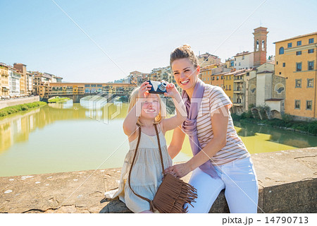 Mother and baby girl taking photo while standing on bridge overl 14790713