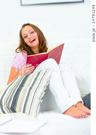 Laughing attractive woman sitting on couch with book. Laughing attractive woman sitting on couch with book. 14791249