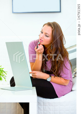 Charming woman sitting in front of mirror and applying lipstick . 14791365