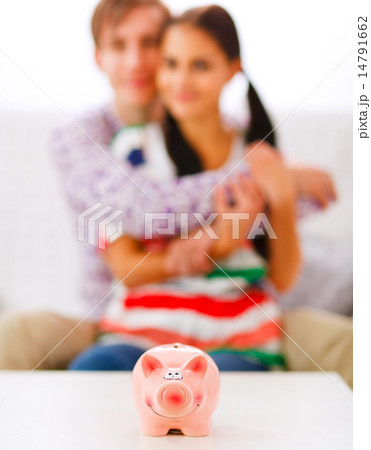 Piggy bank on table and happy young couple in background 14791662