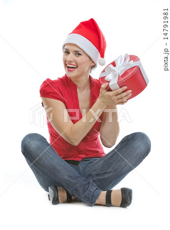 Happy young woman in Christmas hat sitting on floor with present Happy young woman in Christmas hat sitting on floor with present 14791981