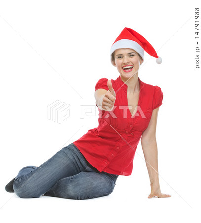 Happy woman in Christmas hat sitting on floor and showing thumbs 14791988