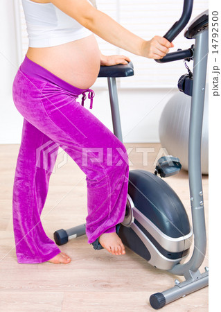Pregnant female preparing for workout on stationary bicycle. Close-up.. 14792500