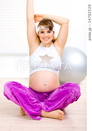 Smiling beautiful pregnant woman making gymnastics at living room. Smiling beautiful pregnant woman making gymnastics at living room. 14792520