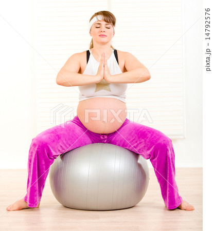 Beautiful pregnant woman doing pilates exercises on gray ball at home. Beautiful pregnant woman doing pilates exercises on gray ball at home. 14792576