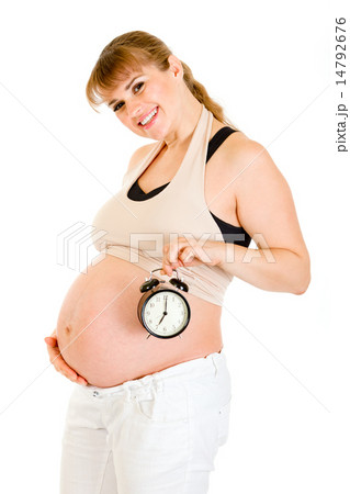 Smiling pregnant woman holding alarm clock near her belly. Smiling pregnant woman holding alarm clock near her belly. 14792676