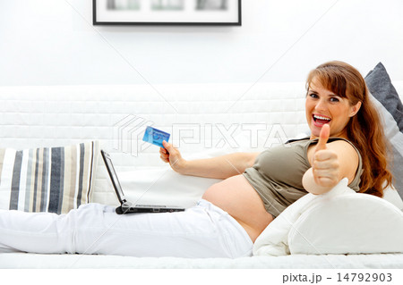 Smiling beautiful pregnant woman using credit card to shop from net and showing thumbs up gesture. 14792903