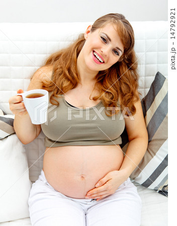 Smiling beautiful female woman relaxing on sofa and holding cup of tea in hand. 14792921