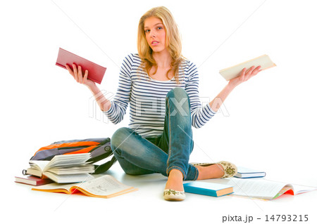 Confused teenager sitting on floor among schoolbooks Confused teenager sitting on floor among schoolbooks 14793215
