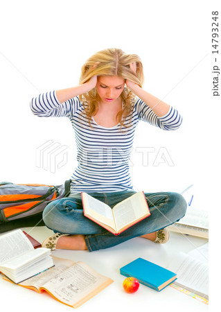 Teen girl sitting on floor among schoolbooks and studying hard 14793248