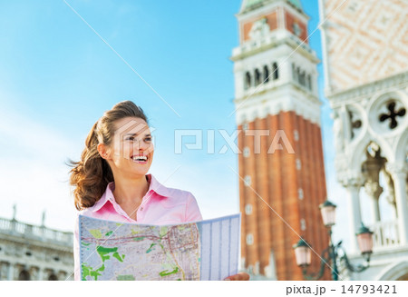 Portrait of smiling young woman looking at map against campanile 14793421
