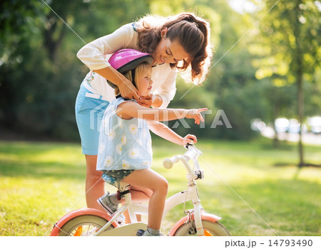 Mother wearing helmet on baby girl on bicycle 14793490