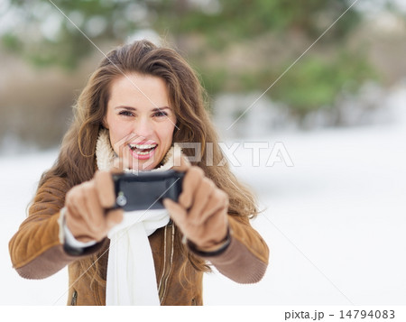 Smiling young woman making photo in winter park Smiling young woman making photo in winter park 14794083
