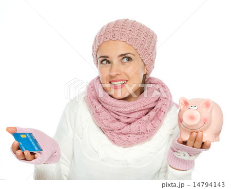 Confused woman in knit winter clothing holding credit card and p 14794143