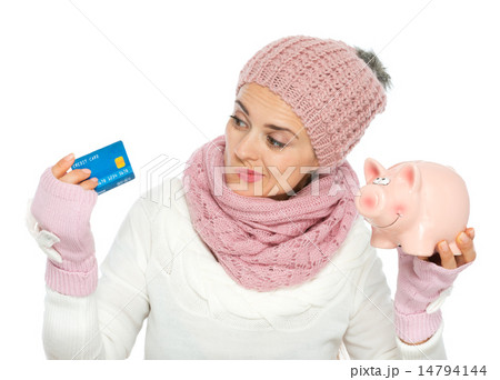 Confused woman in knit winter clothing holding credit card and p Confused woman in knit winter clothing holding credit card and p 14794144