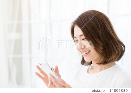 部屋でスマホを見る女性  14805380