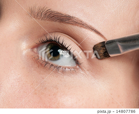 Woman applying cosmetic paint brush on eye zone 14807786