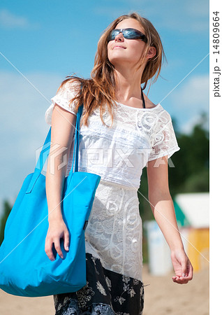 woman walking on sand beach with bag 14809664