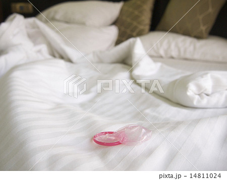 Messy bed in a hotel with a pink condom 14811024