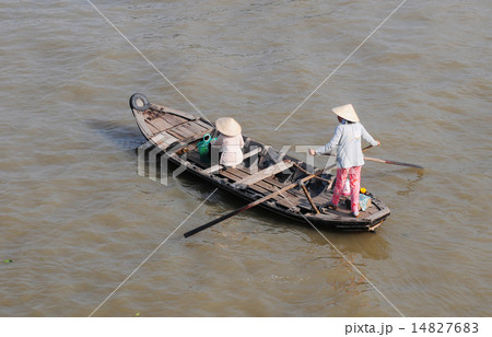 Woman standing and rowing her small boat Woman standing and rowing her small boat 14827683