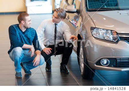 Sales consultant points to the wheel of car talking Sales consultant points to the wheel of car talking 14841528