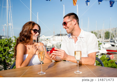 smiling couple with champagne and gift at cafe 14871473