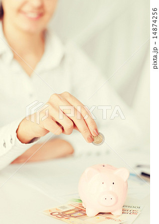woman hand putting coin into small piggy bank woman hand putting coin into small piggy bank 14874256