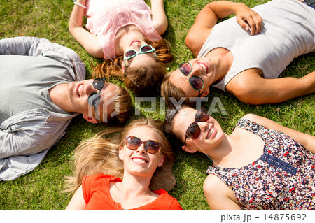 group of smiling friends lying on grass outdoors 14875692