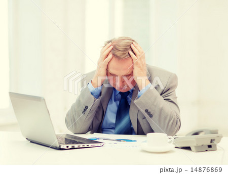 upset older businessman with laptop and telephone 14876869
