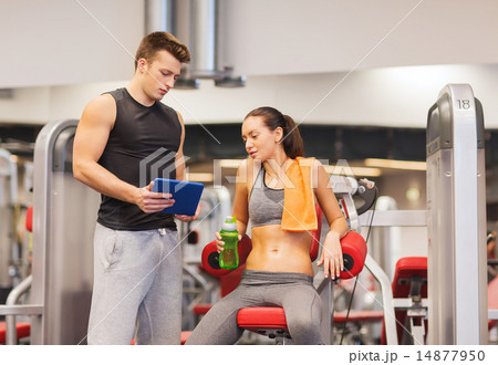 smiling young woman with personal trainer in gym smiling young woman with personal trainer in gym 14877950
