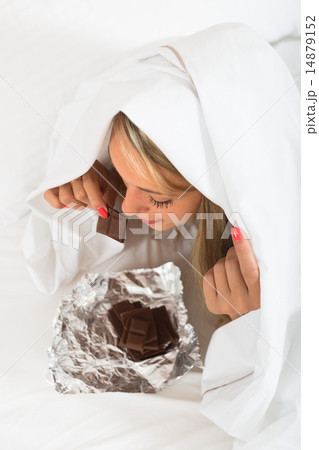 Woman eating chocolate in bed Woman eating chocolate in bed 14879152