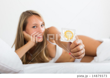 Blonde woman with condom on white lingerie on bed 14879373