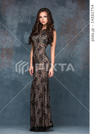 Beautiful young brunette woman with her hair posing in a i long dress. Studio, on gray background Beautiful young brunette woman with her hair posing in a i long dress. Studio, on gray background 14882754