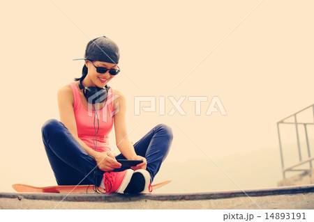 woman skateboarder listening music from cellphone  14893191