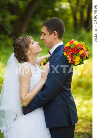 Happy bride, groom standing in green park 14904996