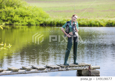 young woman fishing on pier at pond 14919077