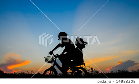 Boy with his sister riding bicycle on sunset  14983208