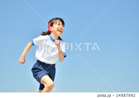 青空で走る女の子 体操服 の写真素材